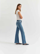 Medium blue mid-rise flare jeans, modeled from hip to floor, showing standard pockets and belt loops.