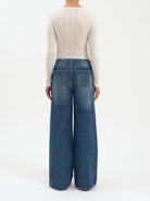 Medium blue, mid-rise wide leg jeans, shown from the back with fading and two pockets.