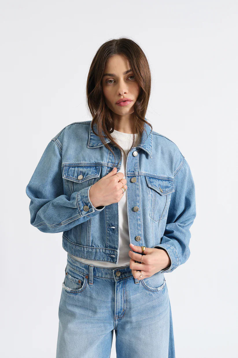 Light blue cropped jean jacket with silver buttons, a collar, and two flap chest pockets.