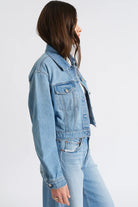Light blue, cropped denim jacket with classic collar, button-front, and two chest pockets on a model.