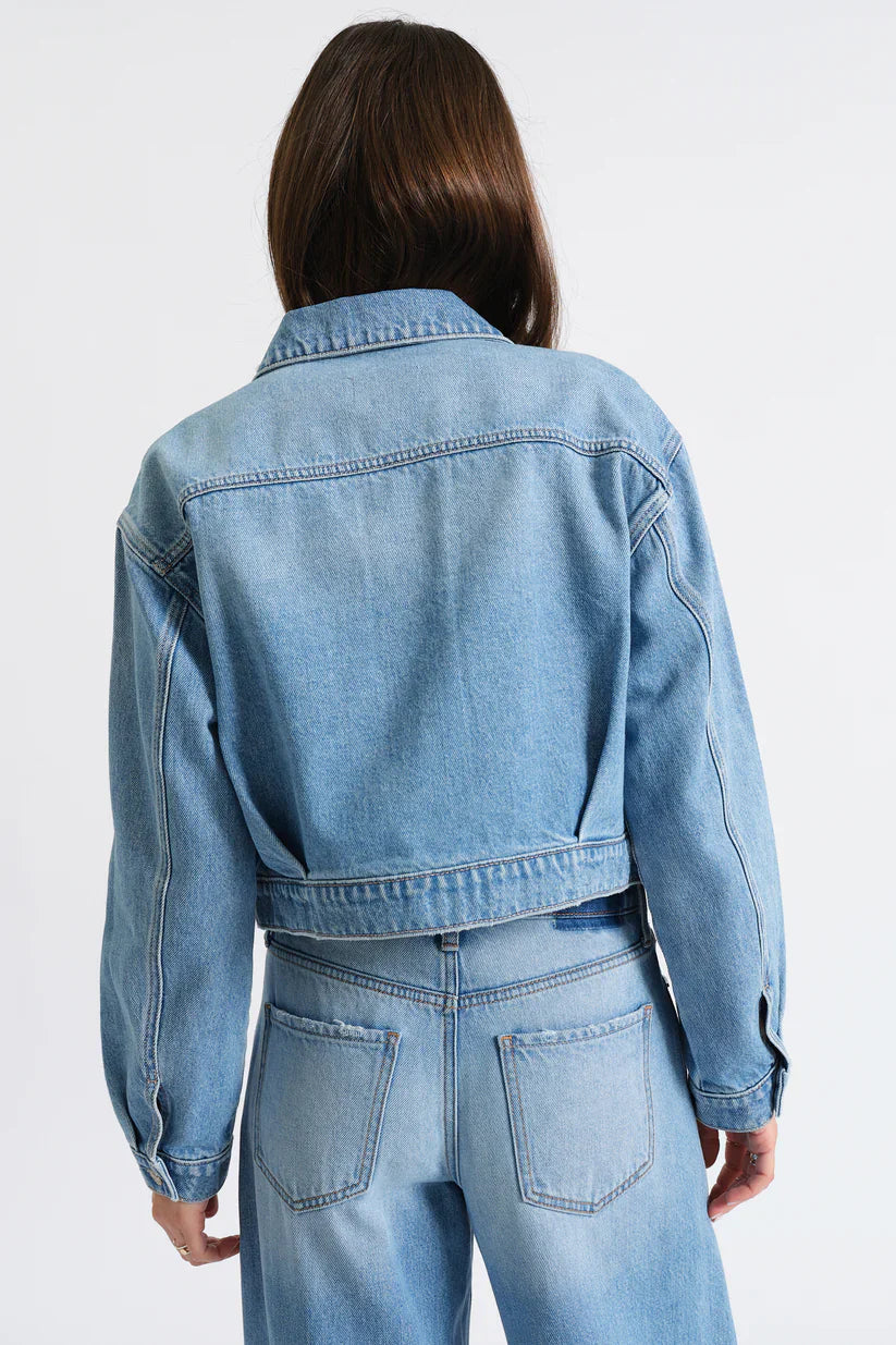 Light blue cropped denim jacket, back view. Features a collar, yoke seam, and waistband.