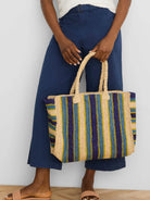 Woven tote with beige, navy, light blue, and lime green vertical stripes. Woven handles.