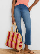 Woven tote bag with vertical stripes in dark red, light pink, and thin yellow on a beige background, with woven handles.