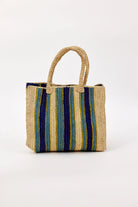 Woven straw tote with vertical stripes: natural, navy, teal, and thin yellow-green. Matching woven handles.