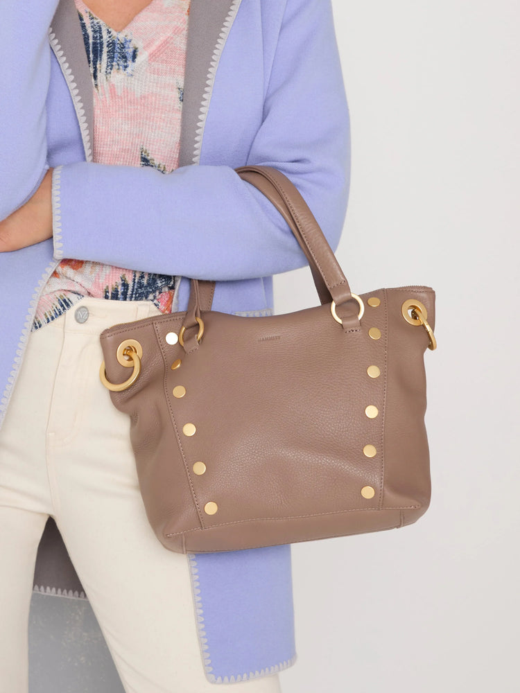 Medium taupe pebbled leather satchel bag with gold studs, two top handles, and a top zipper.