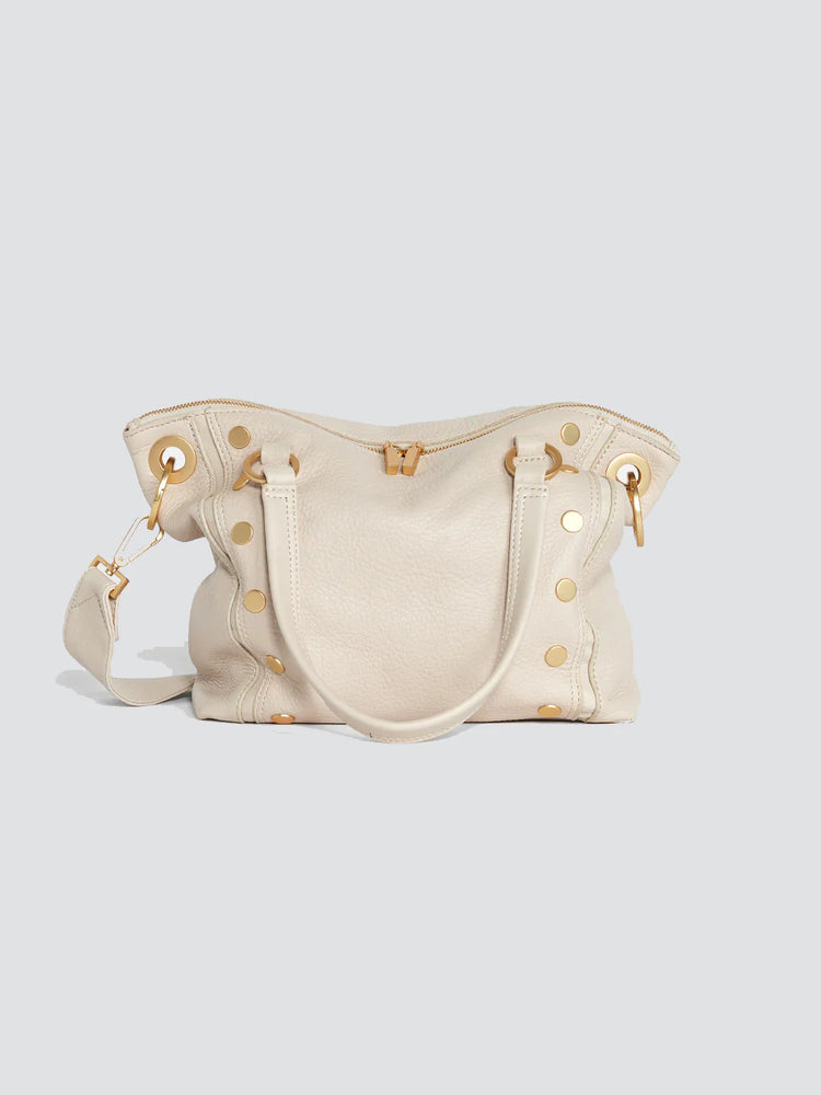 Off-white pebbled leather satchel with top handles, shoulder strap, top zipper, and numerous gold studs and hardware.