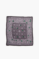 Dark grey bandana with white paisley patterns, scattered bright green embroidered flowers, and a black border.