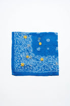 Folded blue bandana with white paisley print and yellow embroidered flowers.
