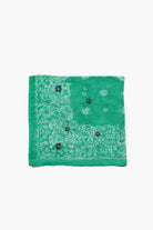 Folded green bandana with white paisley print and three small blue embroidered flowers with yellow centers.