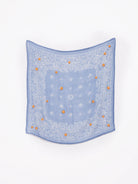 Light blue bandana with white paisley pattern and small orange embroidered flowers.
