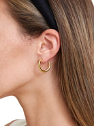 A thick, rounded, bright gold hoop earring with a polished finish.
