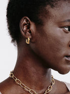 Small gold hoop earring with a wrapped design, shown worn on an earlobe.