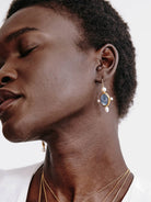 Gold drop earring with an oval blue kyanite stone framed by four white pearls.