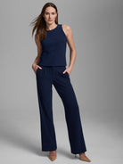 Model wears a navy blue high neck sleeveless tank with smooth, structured fabric.