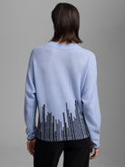 Light blue sweater, back view. Black irregular vertical lines pattern across the bottom. Black trim.