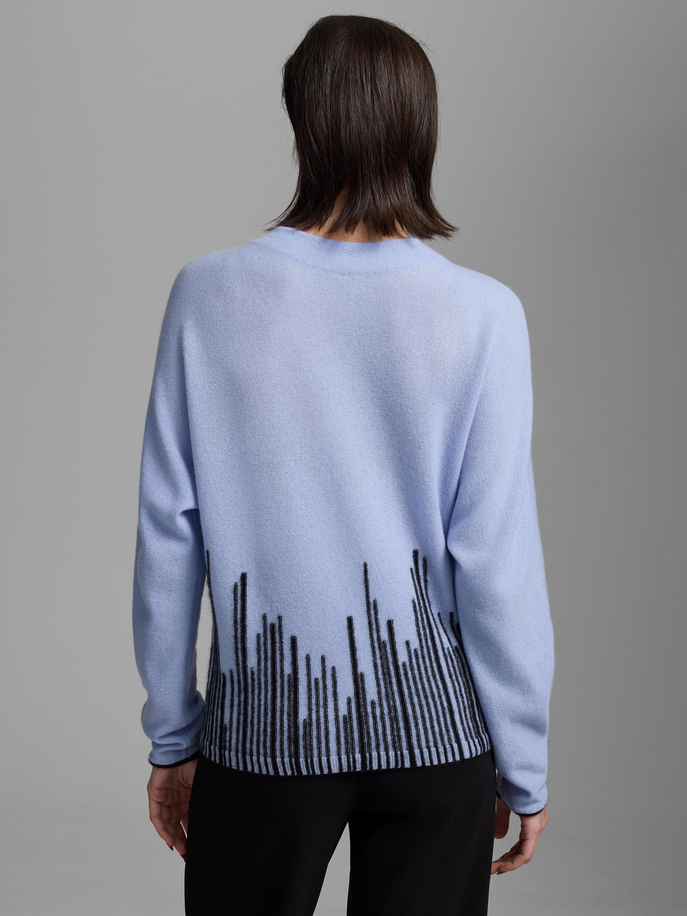 Light blue sweater, back view. Black irregular vertical lines pattern across the bottom. Black trim.