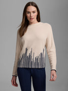 Cream cashmere sweater with dark blue flame stitch pattern (irregular vertical lines) at hem; navy cuff trim.