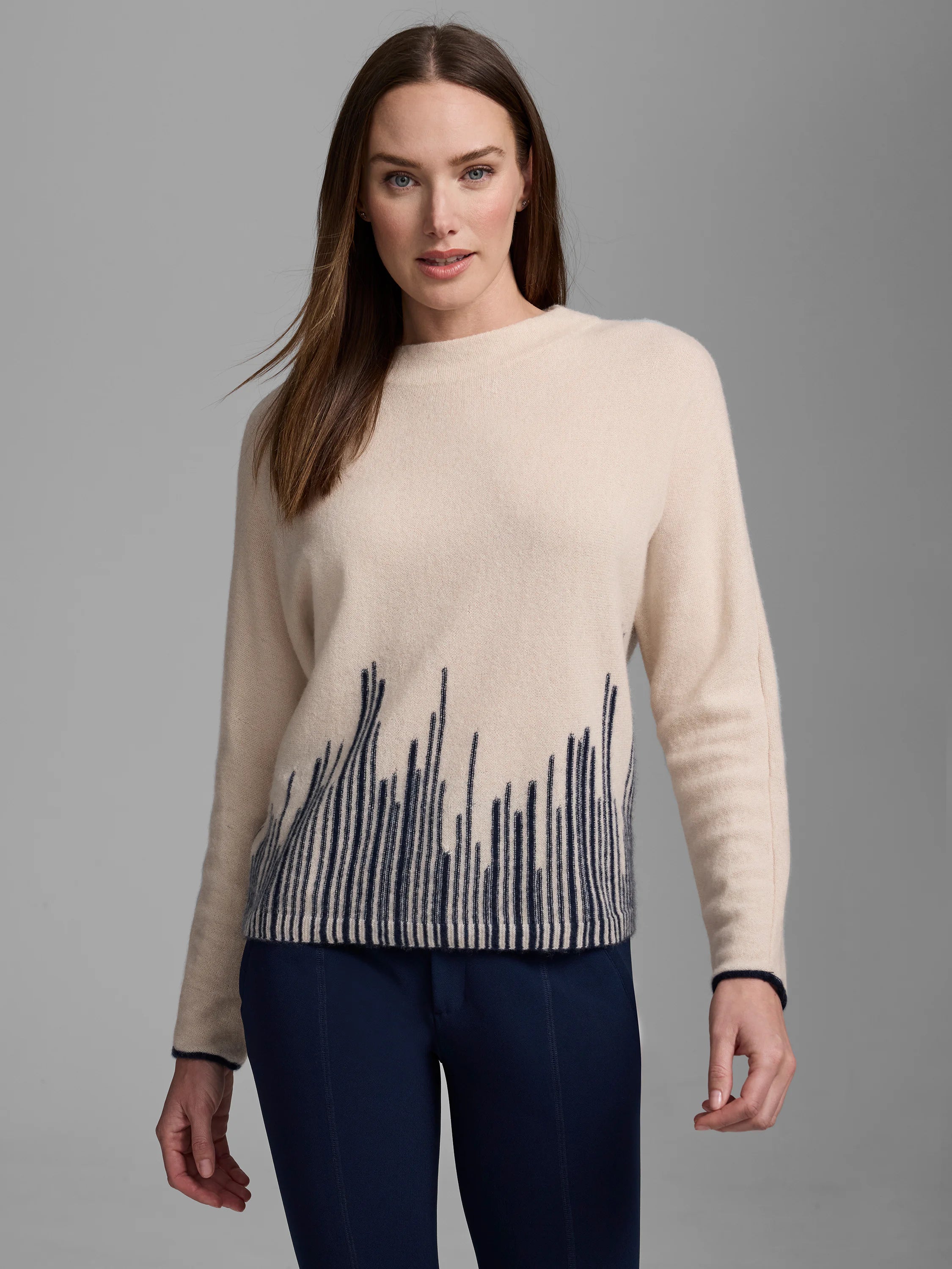 Cream cashmere sweater with dark blue flame stitch pattern (irregular vertical lines) at hem; navy cuff trim.