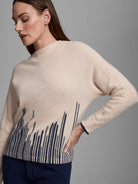 Light beige cashmere sweater featuring a dark blue flame stitch pattern rising from the bottom hem.