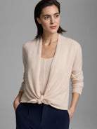 Light beige cashmere cardigan with an open front tied at the waist, worn over a matching tank top.