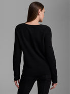Black cashmere sweater, modeled from the back. Features a soft, fuzzy texture, round neck, and ribbed cuffs and hem.