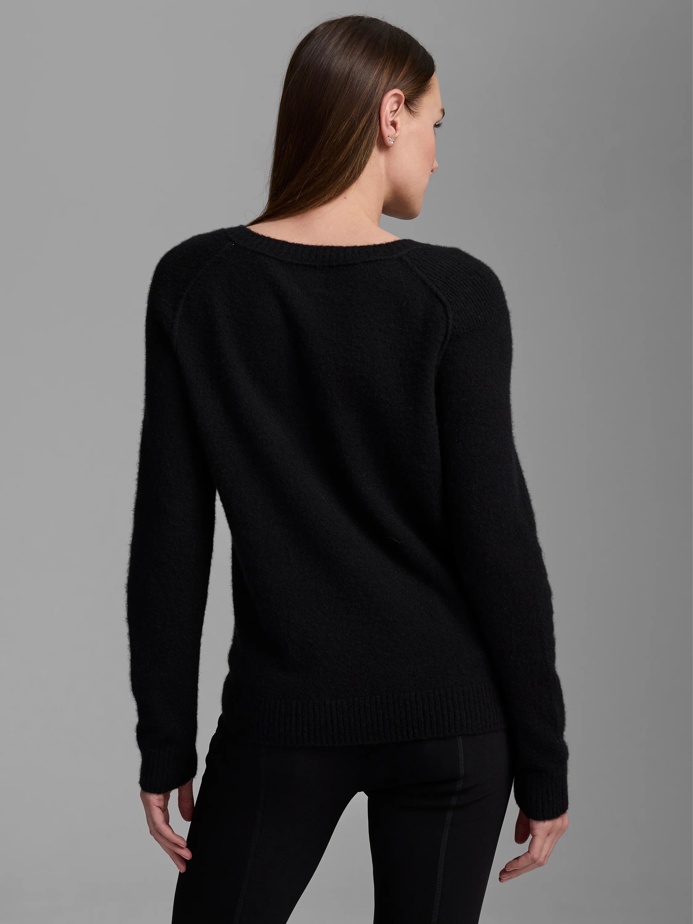 Black cashmere sweater, modeled from the back. Features a soft, fuzzy texture, round neck, and ribbed cuffs and hem.