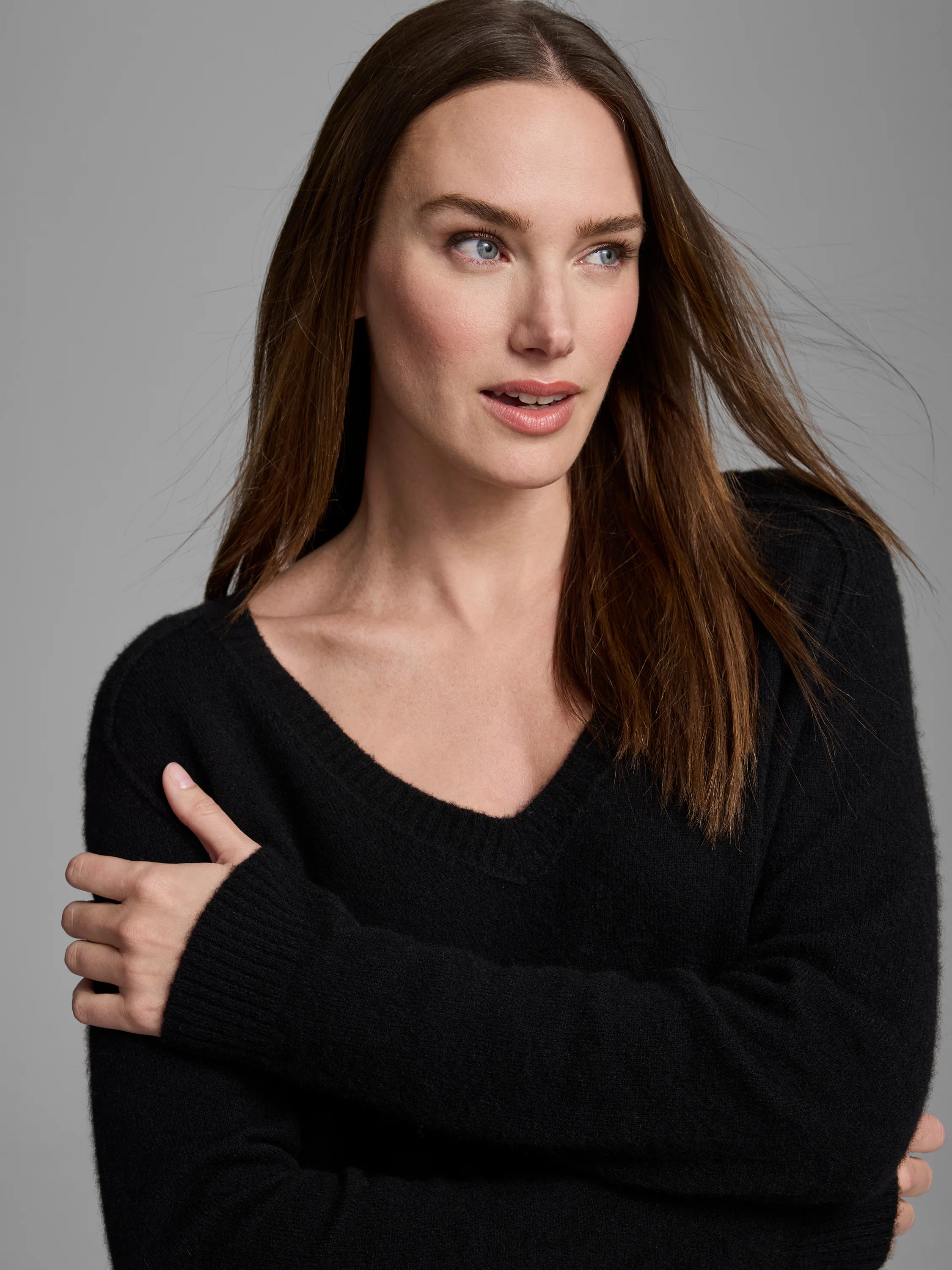 Black cashmere V-neck sweater. Soft, fuzzy texture, with ribbed cuffs on a woman.