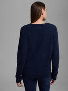Rear view of a model in a navy blue fuzzy sweater with a crew neck, long raglan sleeves, and ribbed cuffs/hem.
