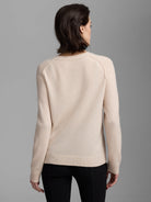 Light beige cashmere sweater, back view on model. Ribbed round neck, raglan sleeves, ribbed cuffs & hem.