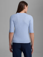 Back of a pale blue cashmere mock neck sweater with elbow-length ribbed sleeves and ribbed hem.