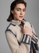 Beige fluffy jacket with dark gray abstract patterns, a high collar, and a zip front.