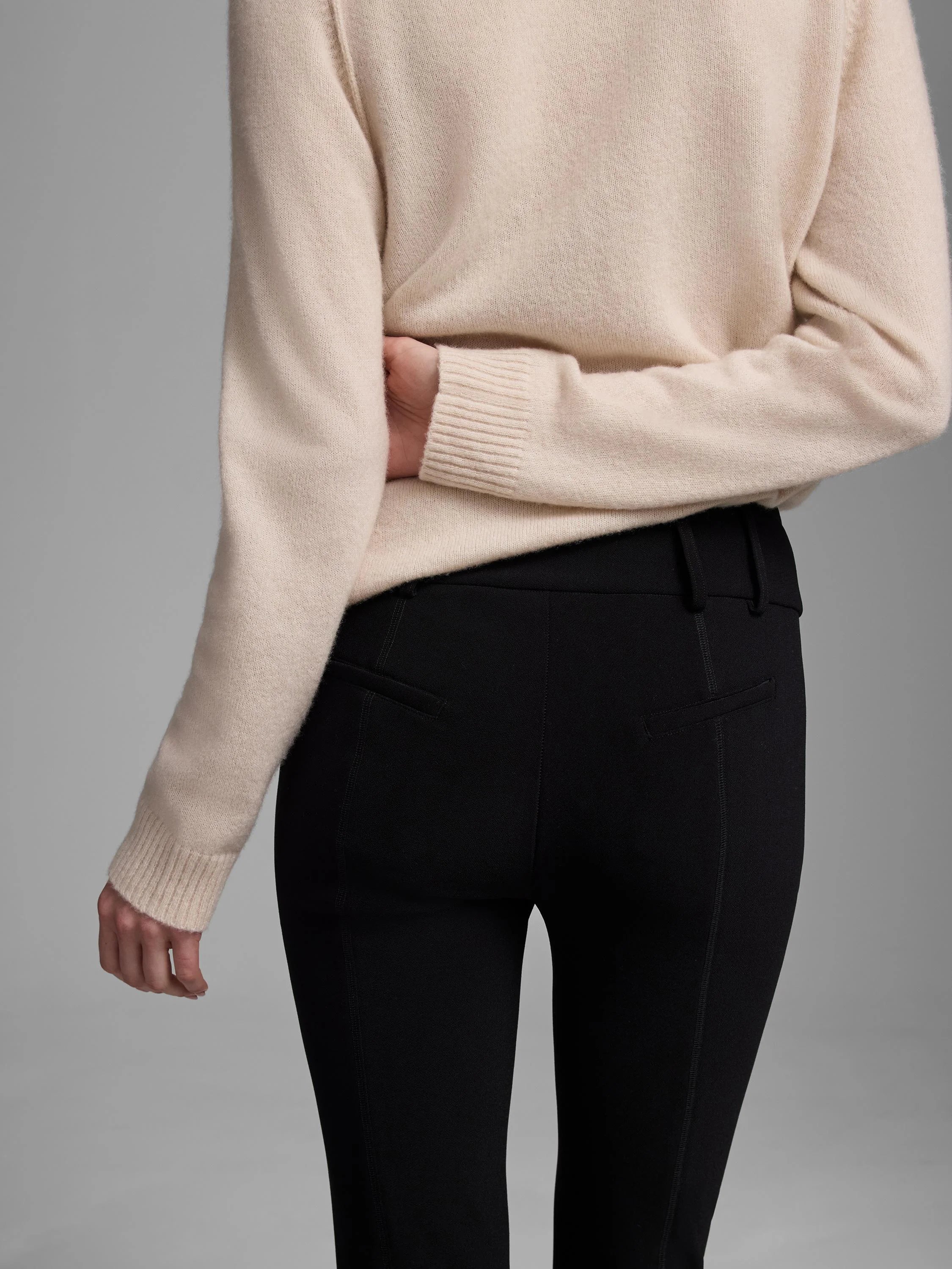 Rear view of black knit scuba slim pants with belt loops and stitched back pocket flaps.