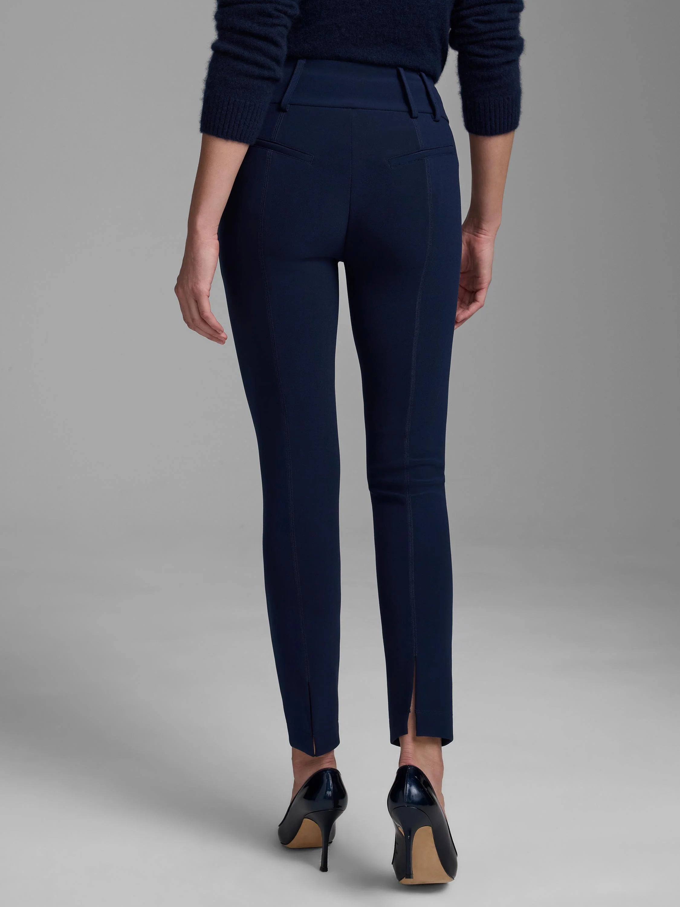 Navy slim-fit scuba knit pants. Features back welt pockets, vertical seams down the legs, and small ankle slits.