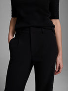 Black wide-leg trousers with pockets, shown on a model wearing a black top.