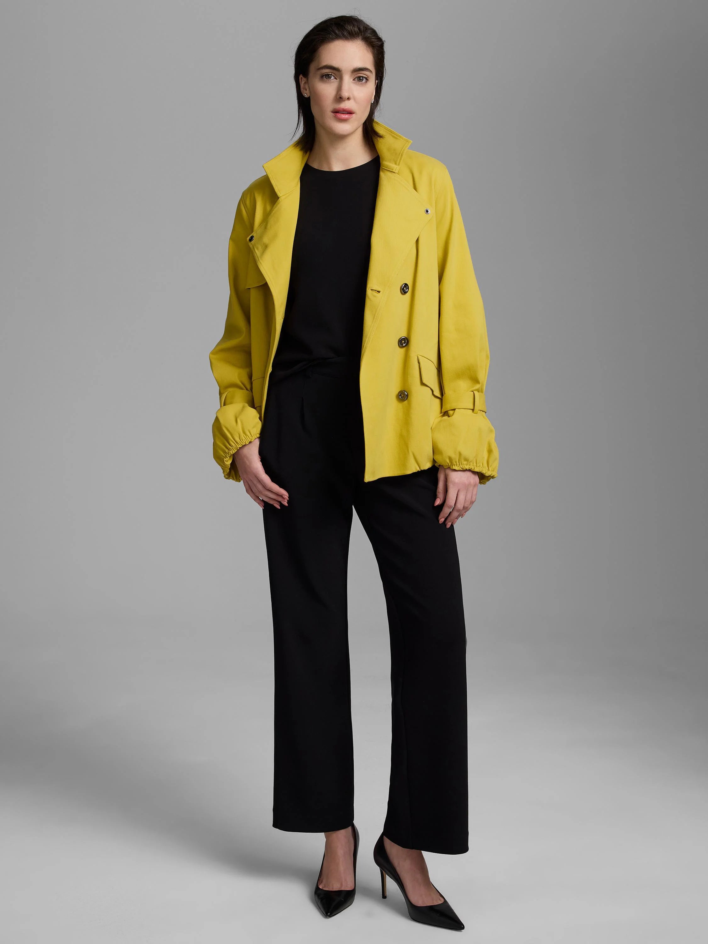 Bright yellow short trench coat, double-breasted with a classic collar, flap pockets, and gathered cuffs.