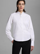 White stretch cotton shirt, band collar, hidden button placket, long sleeves with gathered cuffs.
