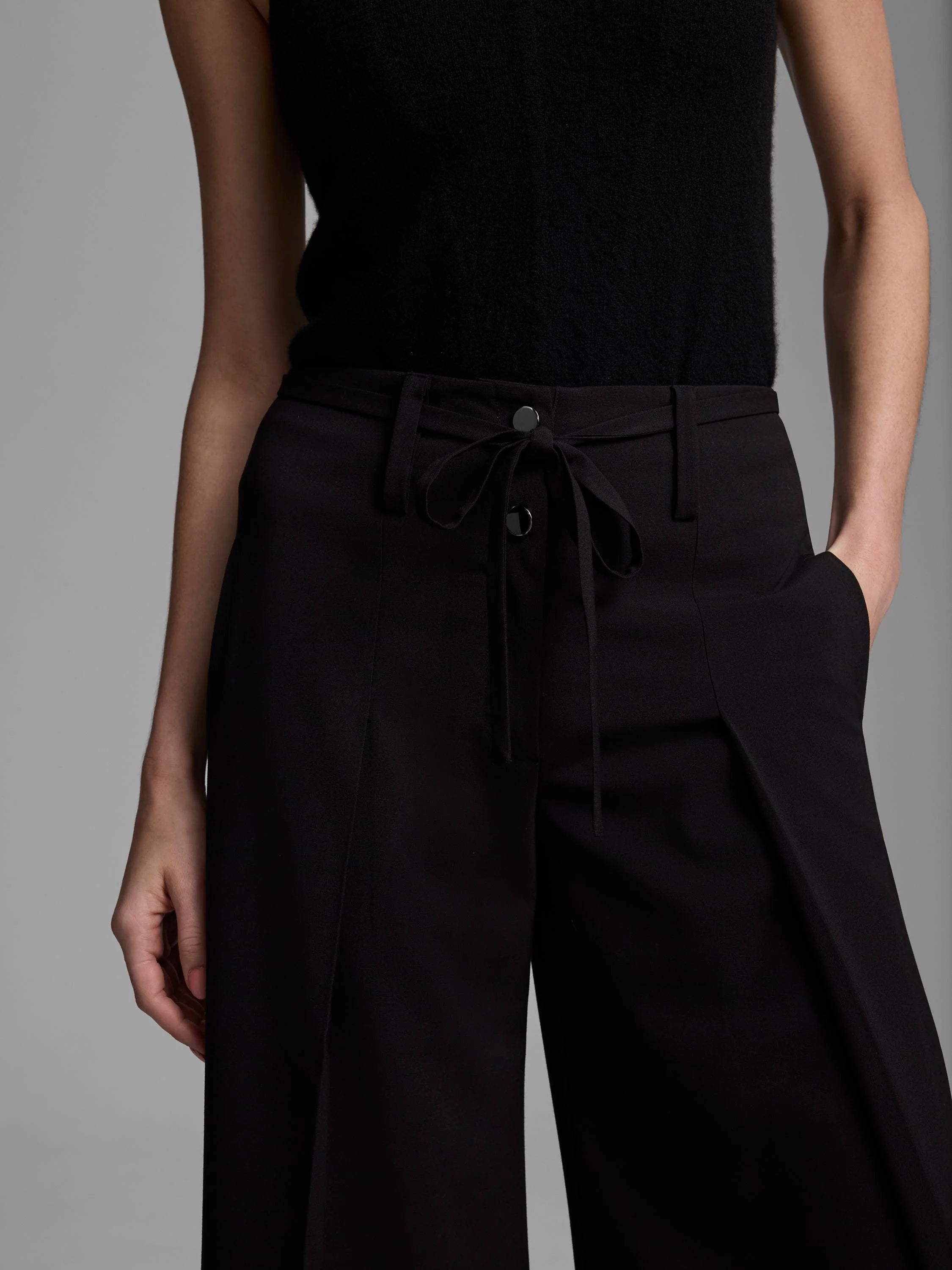 Black apron pant with tie-front waist detail and two black buttons.