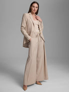 Light beige wide-leg pants with an apron-style tie waist and prominent gold buttons.