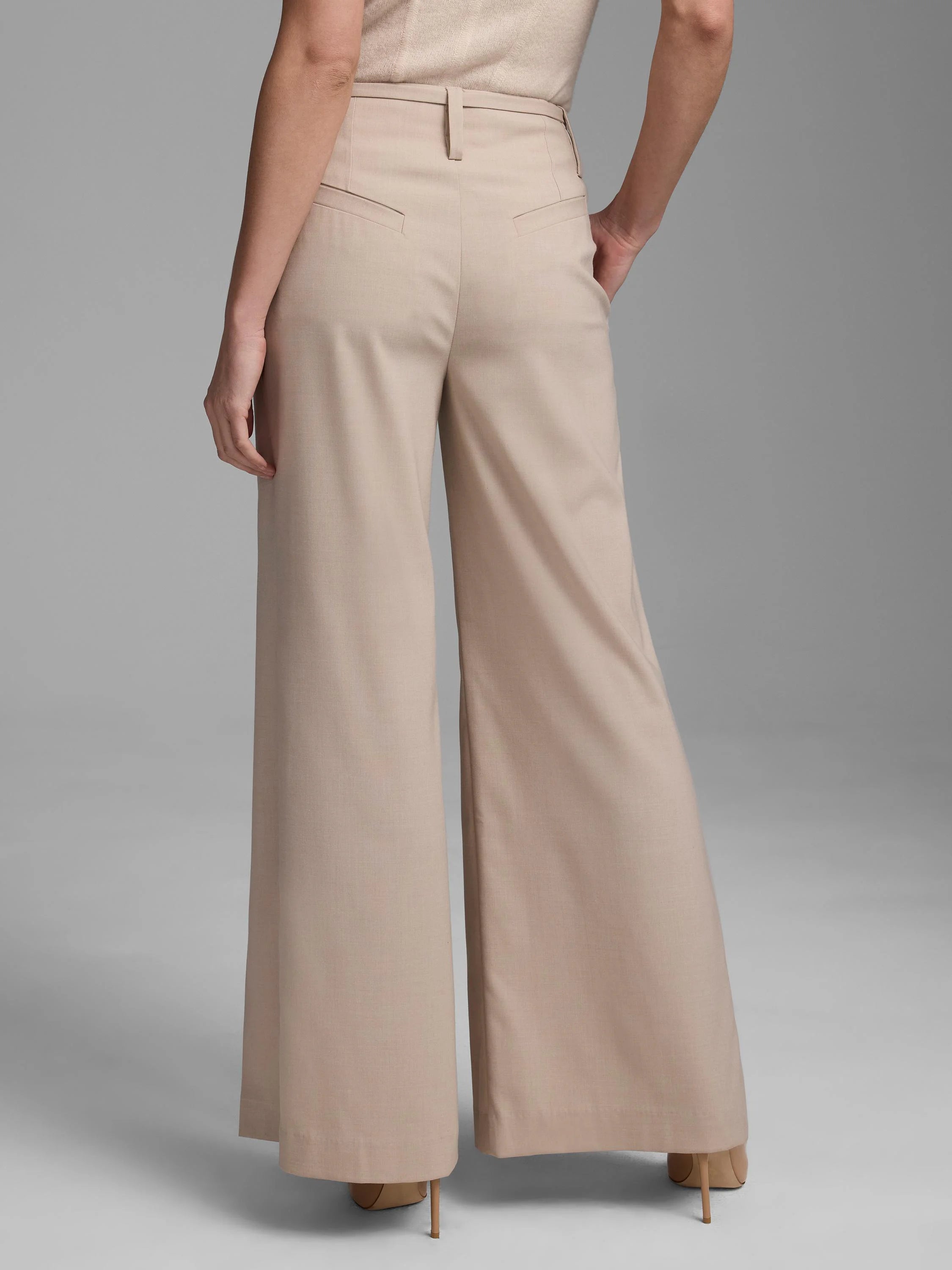 Beige high-waisted wide-leg pants with angled back pockets, shown from behind on a model.