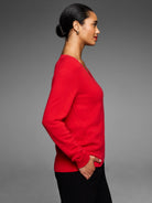 Red V-neck sweater with long sleeves. Smooth, fine knit texture with ribbed cuffs and hem.