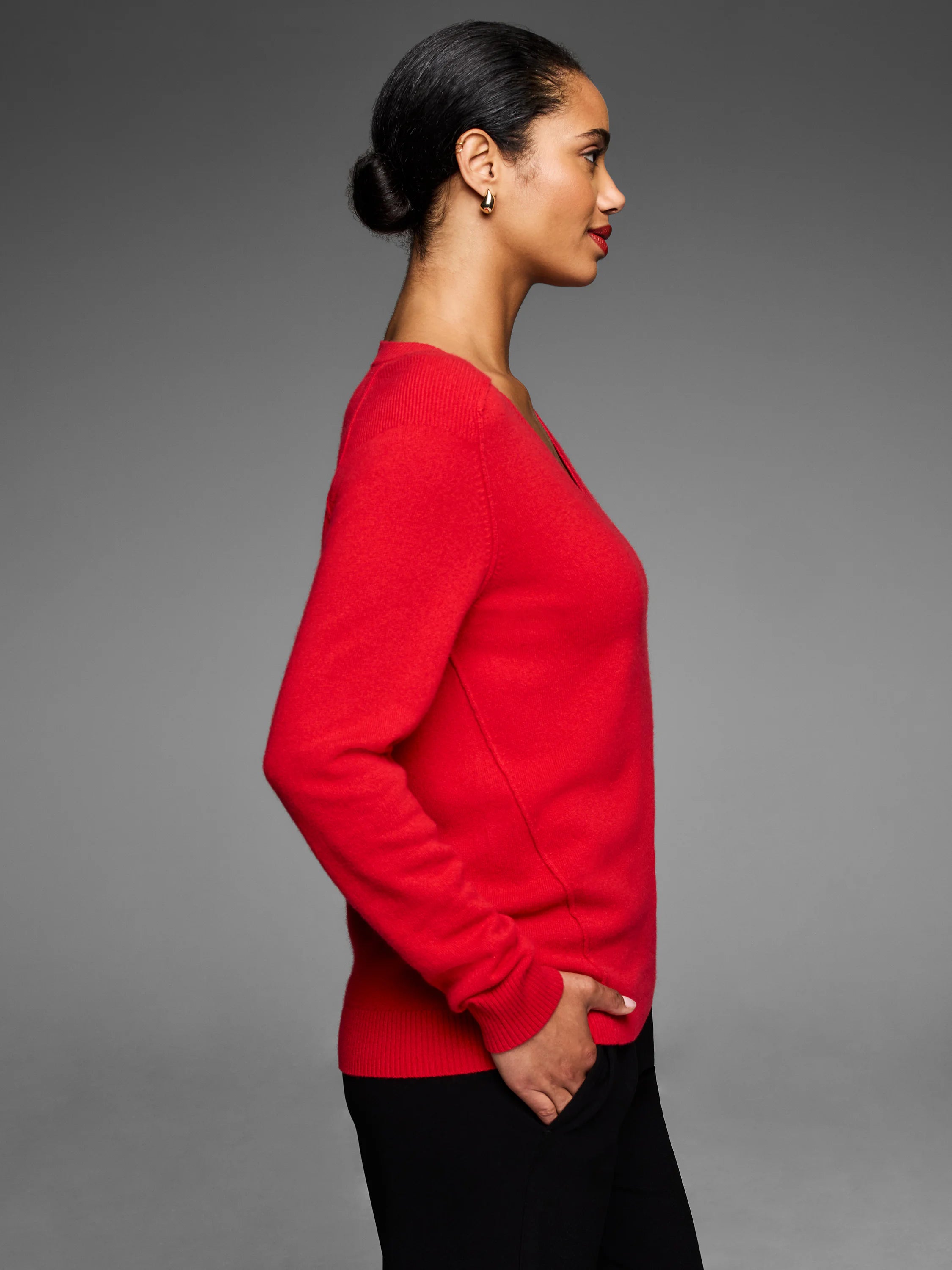 Red V-neck sweater with long sleeves. Smooth, fine knit texture with ribbed cuffs and hem.