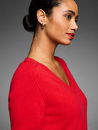 Bright red V-neck sweater on a model. Features a soft, fine knit texture.