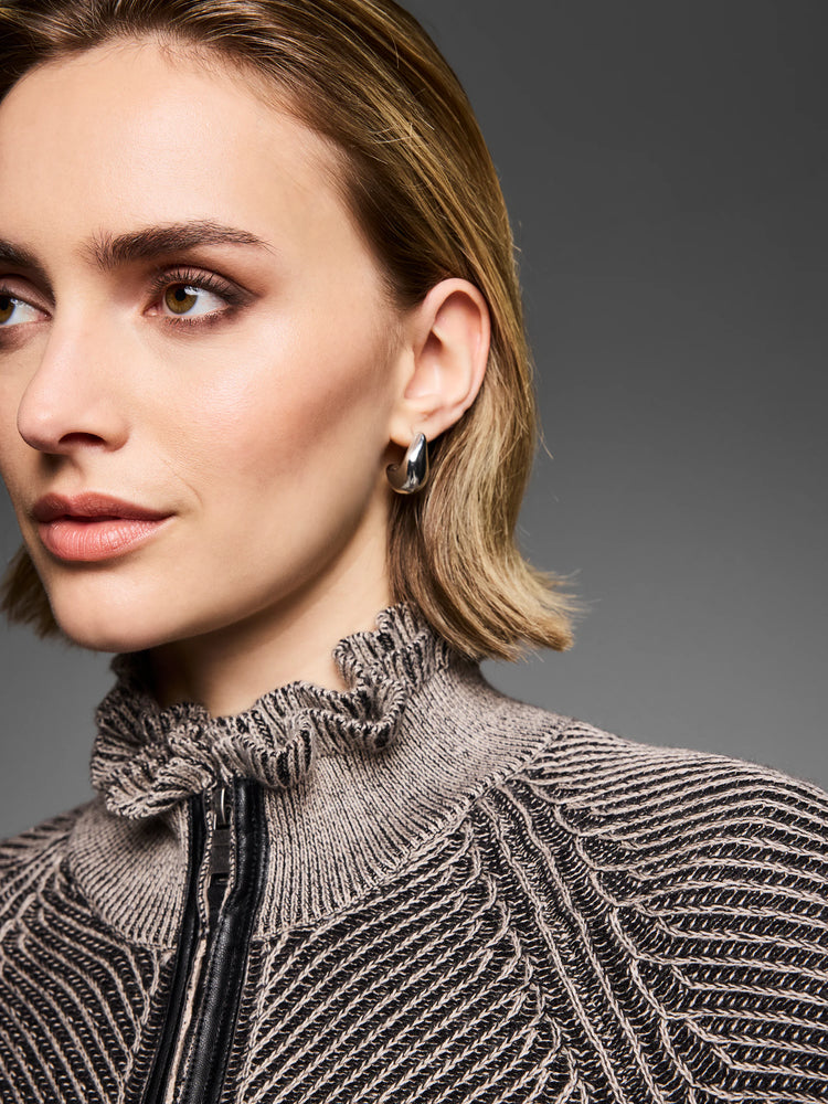 Black and off-white engineered knit cardigan with a ruffled collar, black zipper, and diagonal patterns.