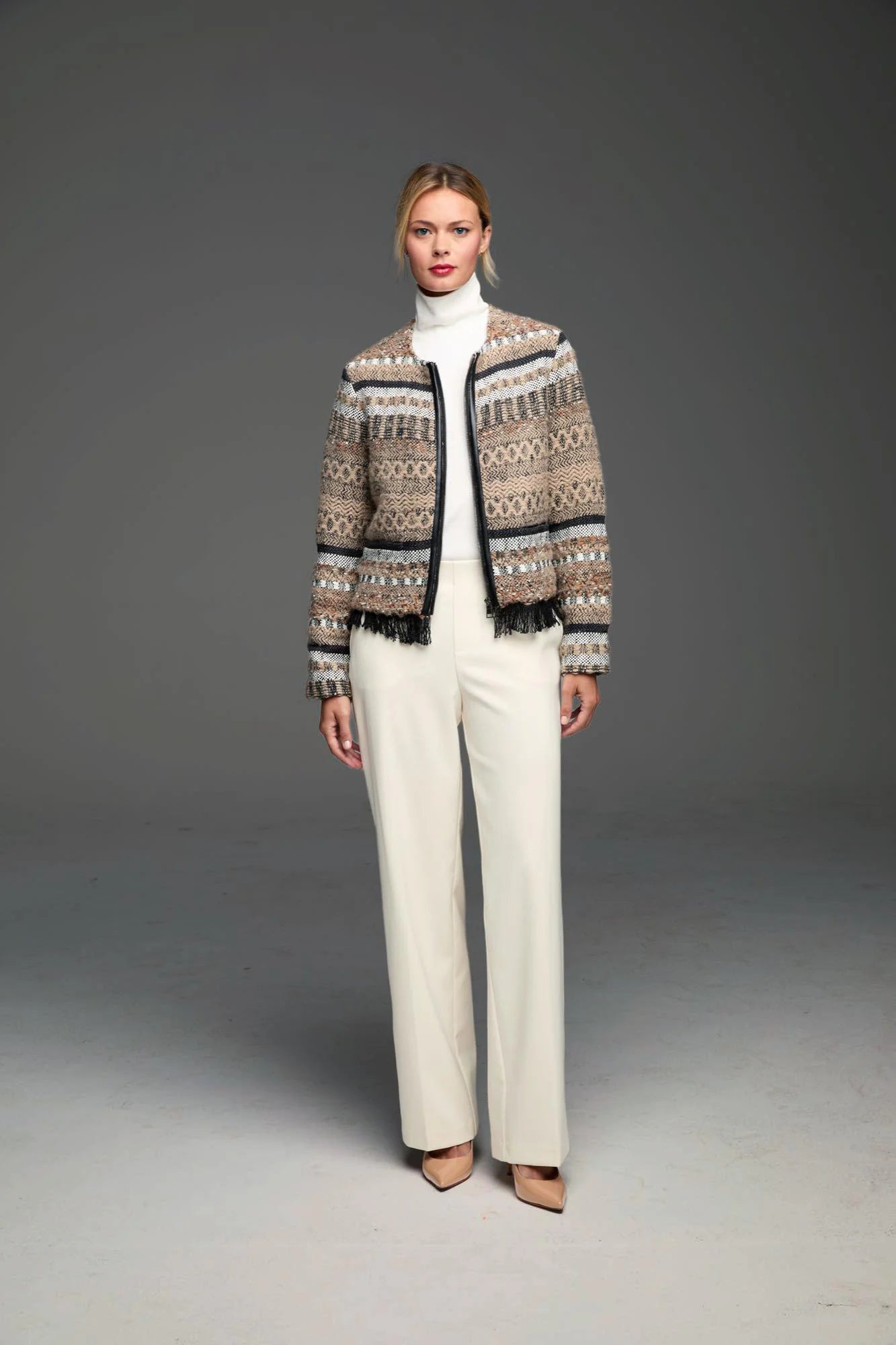 Beige, brown, black, white knit jacket with geometric & stripe patterns, black trim, and fringe hem.