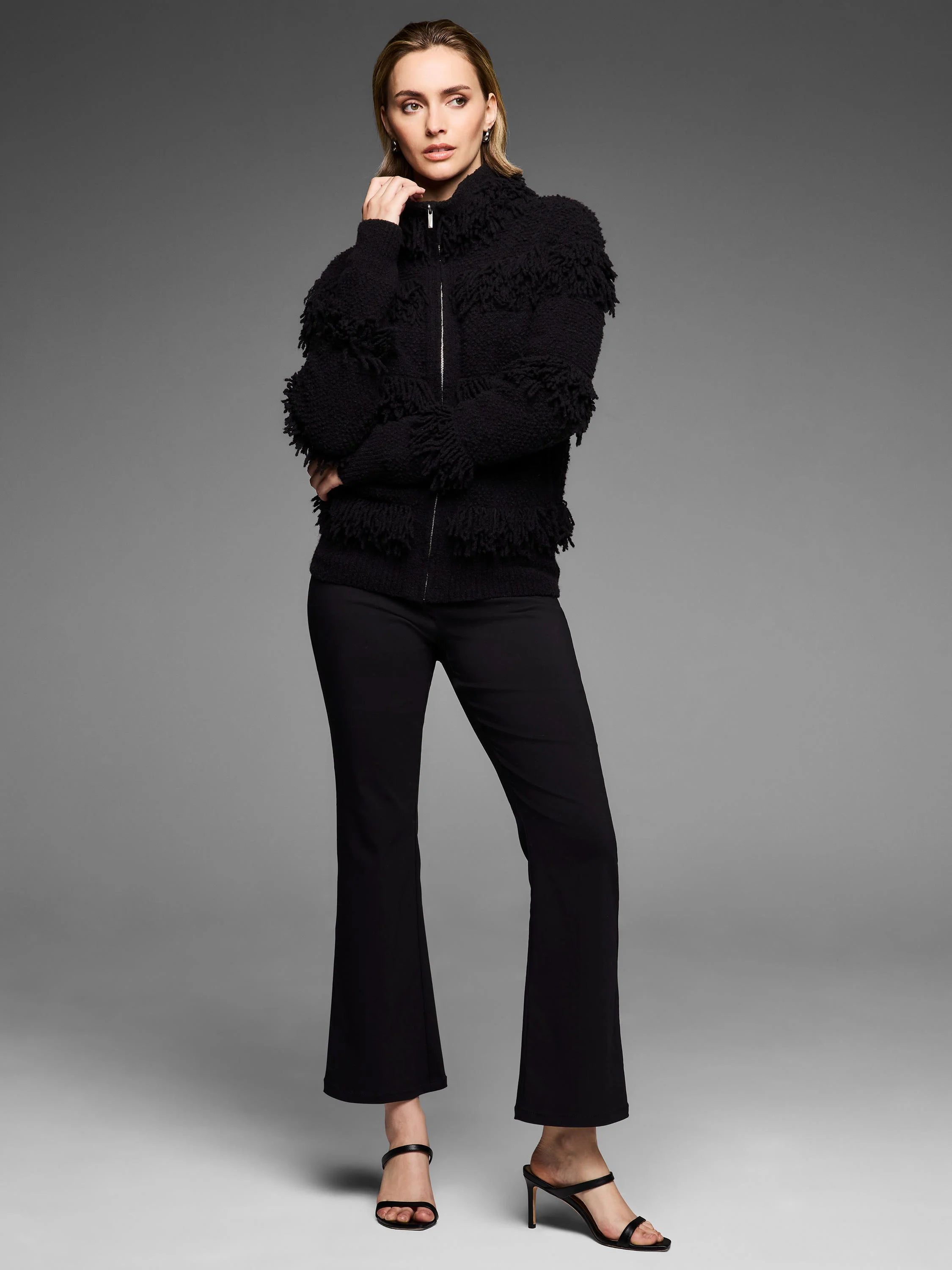 Black jacket featuring dense placed fringe texture and a silver front zipper.
