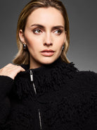 Black jacket with dense, looped fringe texture, high neck, and silver front zipper.