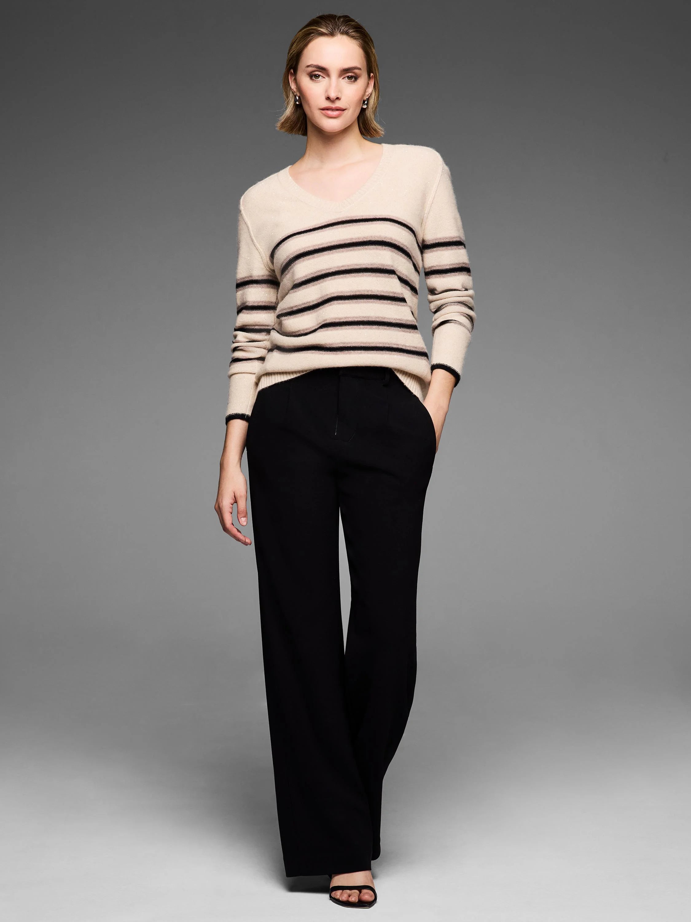 Light beige V-neck sweater with dark horizontal stripes and subtle sparkle flecks.