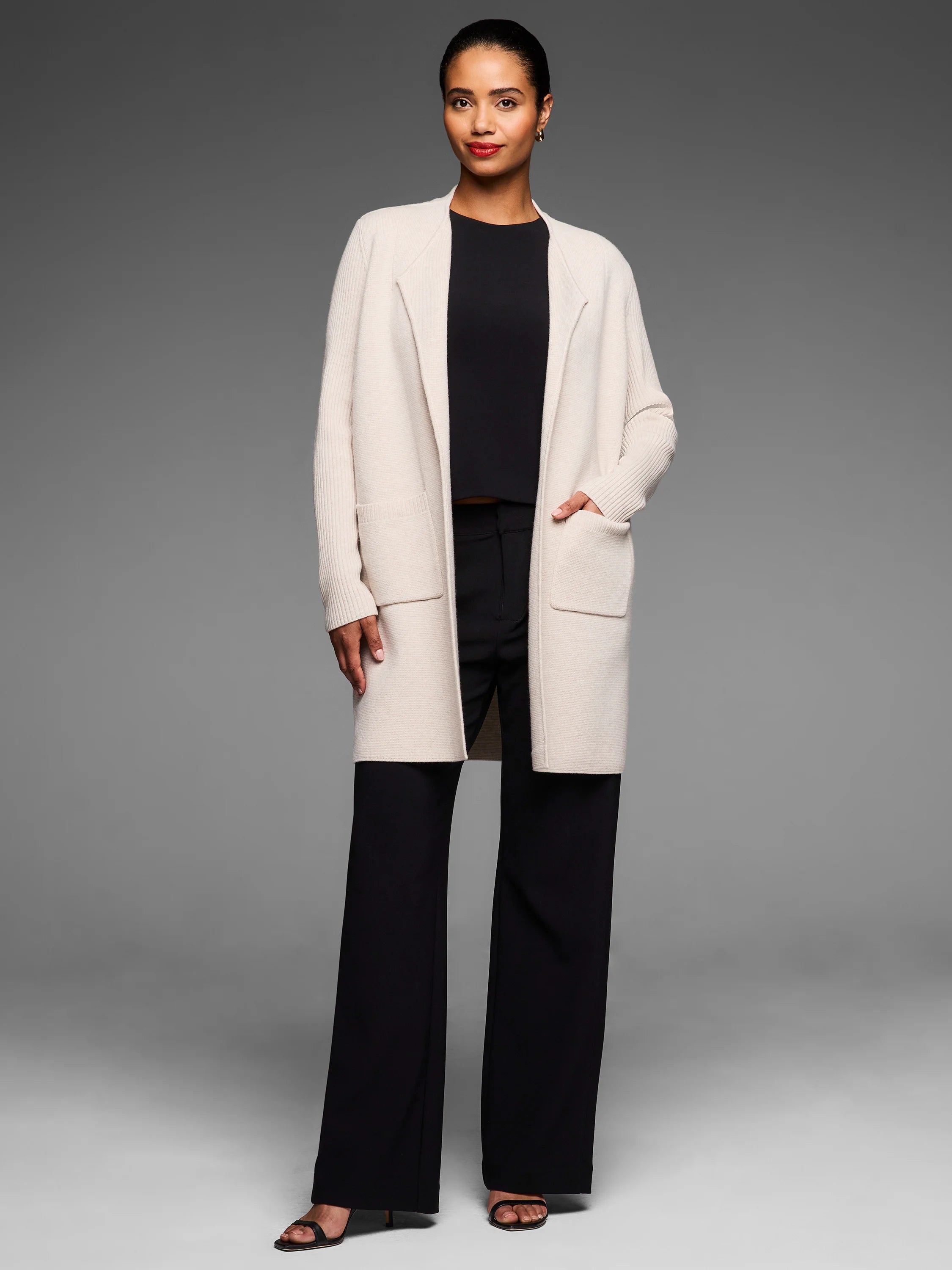 Cream long open knit coat with ribbed sleeves and two large front patch pockets.