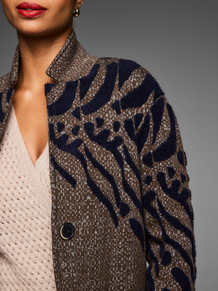 Brown double-knit coat with light flecks, features raised navy blue abstract patterns and one black button.