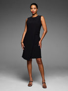 Black sleeveless dress with a round neck, angled knee-length skirt, and a front overlap detail.
